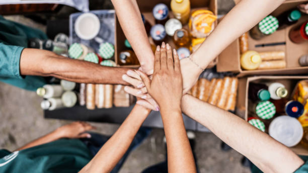 Close-up of volunteers with hands stacked during donation event outdoors
